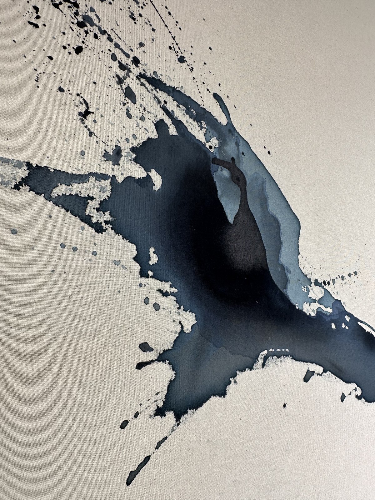 Close detail of a dark ink splash on raw linen by Brenda Rodríguez