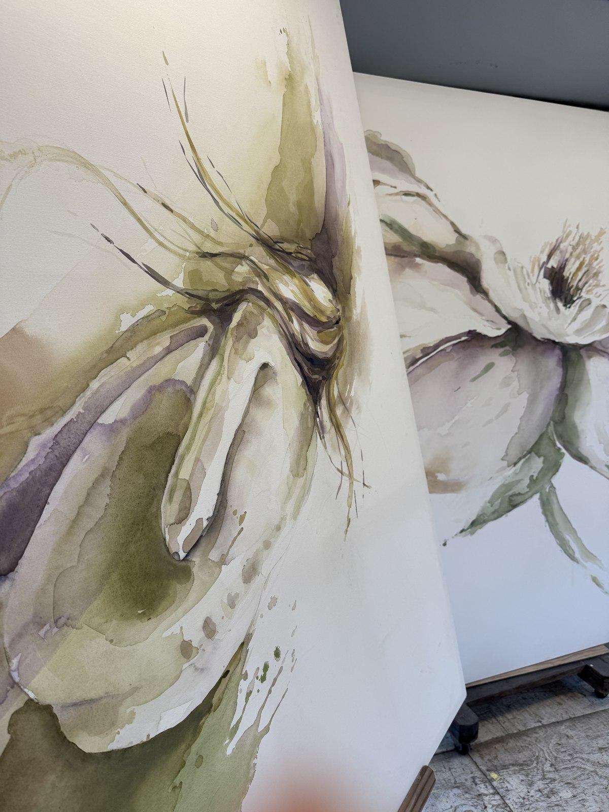 Close angled view of two large flower canvases by Brenda Rodríguez, showing the painted edge and depth